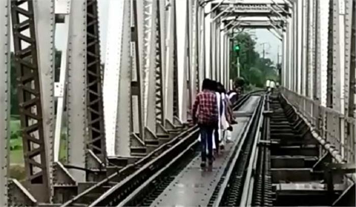 नाले पर डली रेल पटरी को पार कर स्कूल जा रहे बच्चे